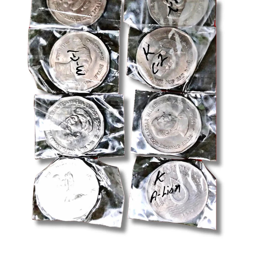 Packaged collectible Indian commemorative coins with historical figures and handwritten labels